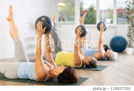 Group of elderly woman doing pilates with soft ball in studio Group of elderly woman doing pilates with soft ball in studio 118827202