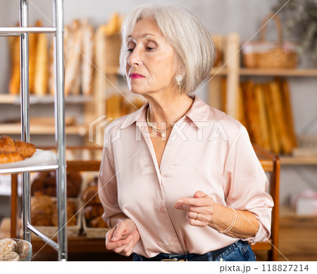 Mature female customer choosing bread and other delicious pastries in bakery 118827214