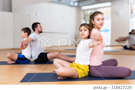 Tween girl with mother doing exercises in pair during family yoga workout 118827220
