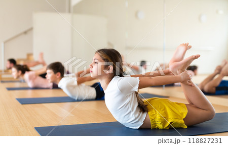Girl exercising bow pose during family yoga training 118827231