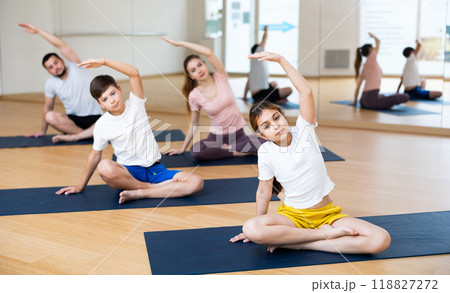 Family doing lotus pose exercises in gym Family doing lotus pose exercises in gym 118827272