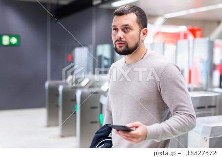 Male passenger in casual clothing near baffle gate in underground platform closeup Male passenger in casual clothing near baffle gate in underground platform closeup 118827372