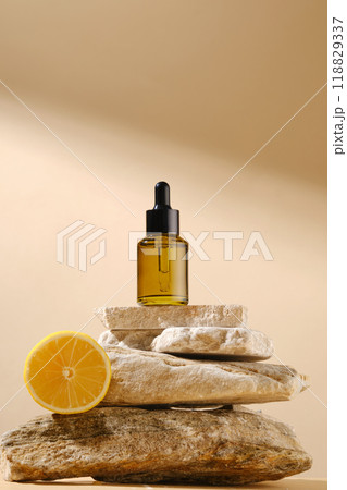 Mockup for advertising with a blank label serum bottle displayed on a stack of stone, against on beige background with many sunshine streaming on. Front view, blank space for text 118829337