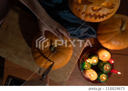 Engaging in the delightful activity of carving pumpkins for a Halloween celebration with candles Engaging in the delightful activity of carving pumpkins for a Halloween celebration with candles 118829673