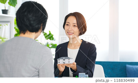 オフィスで住宅模型を持って打ち合わせする二人の女性ビジネスパーソン 118830499