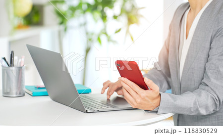 オフィスでノートパソコンとスマホを使う女性ビジネスパーソン オフィスでノートパソコンとスマホを使う女性ビジネスパーソン 118830529