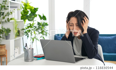 オフィスでノートパソコンを見て悩む女性ビジネスパーソン 118830544