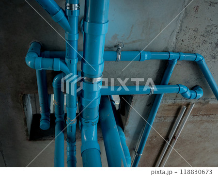 A bright blue pipes attached to a solid concrete wall A bright blue pipes attached to a solid concrete wall 118830673
