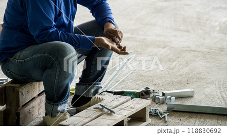 A builder works with screws and nuts on a wooden pallet A builder works with screws and nuts on a wooden pallet 118830692