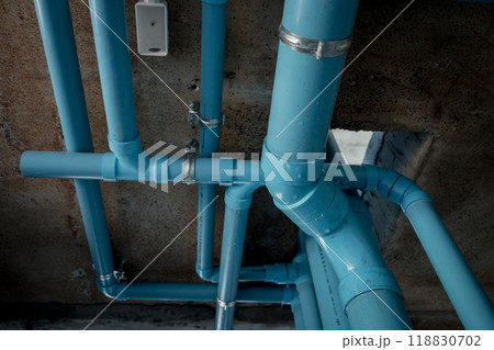 A bright blue pipes attached to a solid concrete wall A bright blue pipes attached to a solid concrete wall 118830702