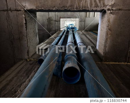 A bright blue pipes attached to a solid concrete wall A bright blue pipes attached to a solid concrete wall 118830744