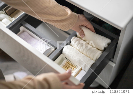 Top view of woman hands neatly organizing bathroom amenities and toiletries in drawer in bathroom. 118831071