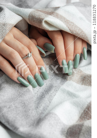 Elegant mint green manicure on long nails adorned with a ring, wrapped in a cozy blanket during a relaxing indoor moment 118831270