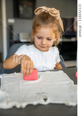 Little girl with a stamp with a name for signing children's things. Identification of personal clothing.  118832115