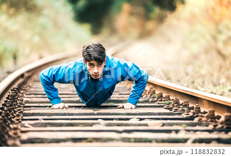Sporty man exercising on old unused rails in the middle of nature. Morning workout for young man. Sporty man exercising on old unused rails in the middle of nature. Morning workout for young man. 118832832