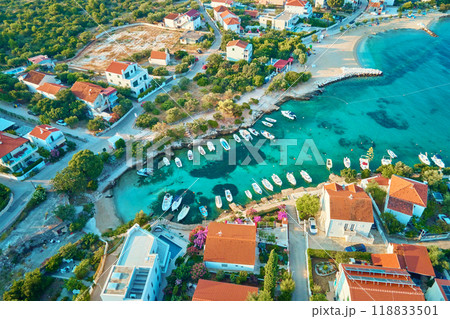 Birds eye view of sea coast with small town along seashore. Aerial top view of coastal village with red-roofed houses and boats near shore. Tourist town Rogoznica in Croatia on Adriatic Sea 118833501