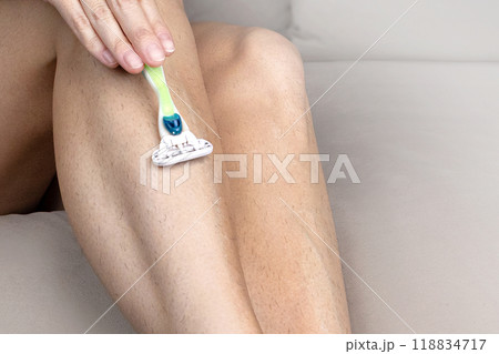 Woman shaves hairy legs with machine. Close up photo 118834717