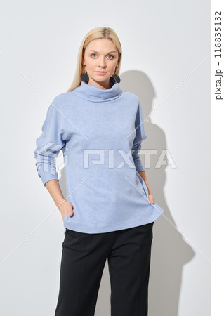 Studio portrait of classy woman in blue sweater and black trousers 118835132