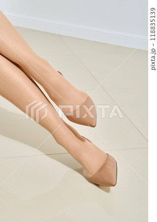 Front view of female legs in beige stilettos 118835139