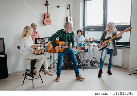 Group of seniors meeting to play musical instruments together in band, having fun. Therapeutic effect of music for elderly people. Group of seniors meeting to play musical instruments together in band, having fun. Therapeutic effect of music for elderly people. 118835249