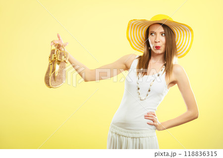 Woman in big yellow summer hat holds sandals Woman in big yellow summer hat holds sandals 118836315