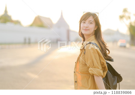 Traveler asian woman in her 30s stands bathed in the golden glow of sunset, embracing the freedom of exploration. on summer holiday weekend vacation trip in Bangkok, Thailand Traveler asian woman in her 30s stands bathed in the golden glow of sunset, embracing the freedom of exploration. on summer holiday weekend vacation trip in Bangkok, Thailand 118839866
