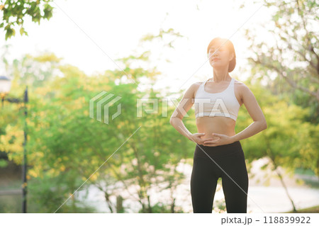 Female jogger. Fit young Asian woman with sportswear stretching muscle in park before running and enjoying healthy outdoor. Fitness runner girl in public park. Wellness being concept 118839922