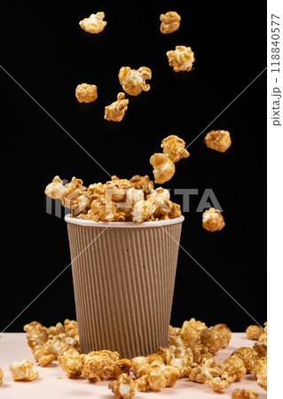 Sweet caramelized popcorn pouring into a glass on a black background. Sweet caramelized popcorn pouring into a glass on a black background. 118840577
