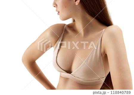 Close-up of female upper body, showing her flawless skin and delicate structure of her nude bra against white studio background. 118840789