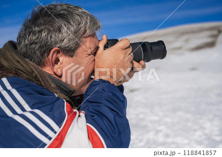 an elderly man with a camera in his hands, photographing a mountain winter landscape an elderly man with a camera in his hands, photographing a mountain winter landscape 118841857