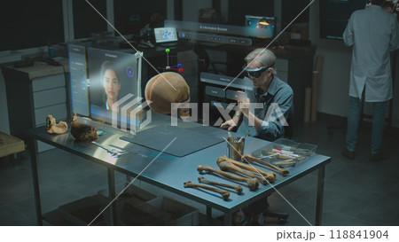 Archaeologist in VR headset studies fossil skull using virtual display with AI assistant 118841904