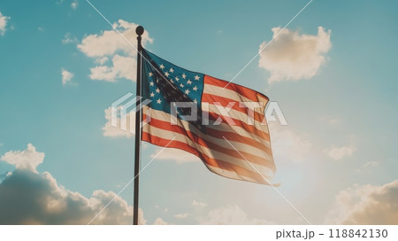 American flag flying in the wind against a blue sky and scattered clouds. Ideal for Veterans Day or Memorial Day. 118842130