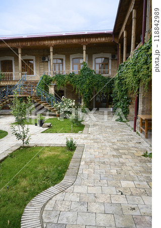 Courtyard of a wooden house with terrace, trees, vineyard  and rose bushes in Samarkand, Uzbekistan 118842989