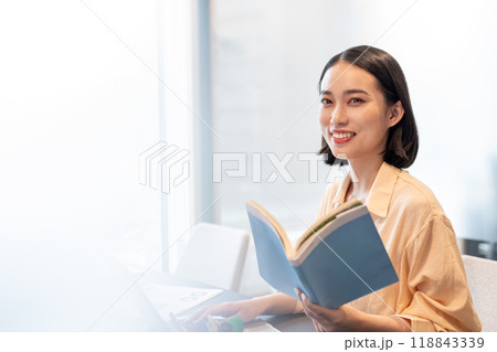 参考書を読みながらパソコン作業をする女性 118843339