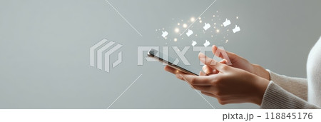 Smartphone held by a female displaying glowing like icons, showing the impact of social media. 118845176