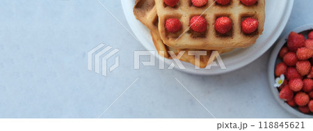 Banner. Belgian or Viennese waffles with strawberries on minimalistic concrete grey background. delicious sweet dish, copy space for text Banner. Belgian or Viennese waffles with strawberries on minimalistic concrete grey background. delicious sweet dish, copy space for text 118845621