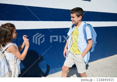 Two children walking outdoors with school backpacks on a sunny day 118845915