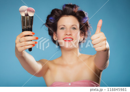 woman in hair rollers holds makeup brushes 118845981