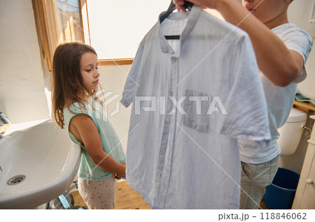 Young siblings handling laundry in a bright bathroom setting Young siblings handling laundry in a bright bathroom setting 118846062