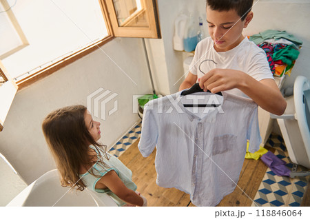 Brother and sister doing laundry in a bright laundry room 118846064
