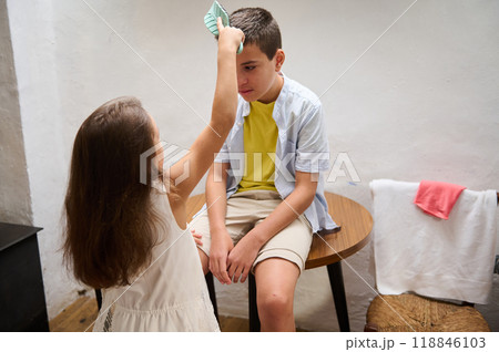 Sister caring for brother with a cool compress at home 118846103
