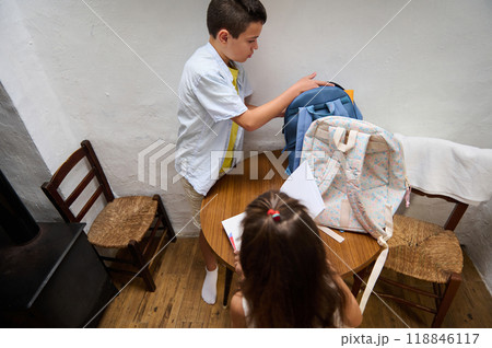 Children preparing backpacks for school in cozy room setting 118846117