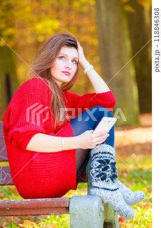 Sad woman in park with phone. 118846308
