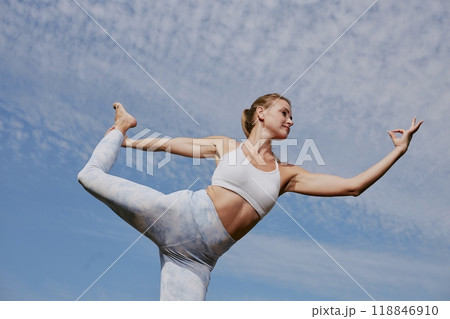 Low angle shot of confident and strong woman holding dancer pose under open sky 118846910