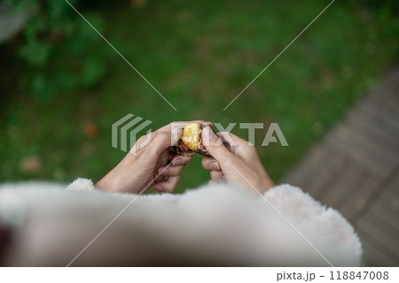 Woman peeling fresh roasted chestnut Woman peeling fresh roasted chestnut 118847008