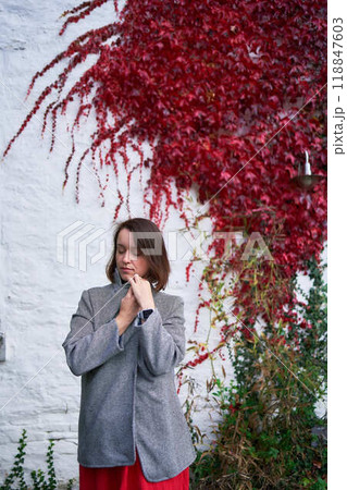30-year-old medium-sized woman in a red muslin dress in an autumn garden 30-year-old medium-sized woman in a red muslin dress in an autumn garden 118847603
