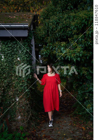 30-year-old medium-sized woman in a red muslin dress in an autumn garden 118847610