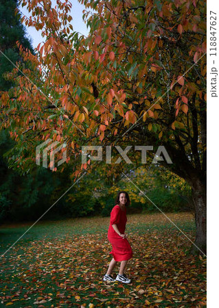 30-year-old medium-sized woman in a red muslin dress in an autumn garden 118847627