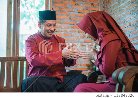 Asian Muslim husband makes hand gestures to wish wife a happy Eid Asian Muslim husband makes hand gestures to wish wife a happy Eid 118848326