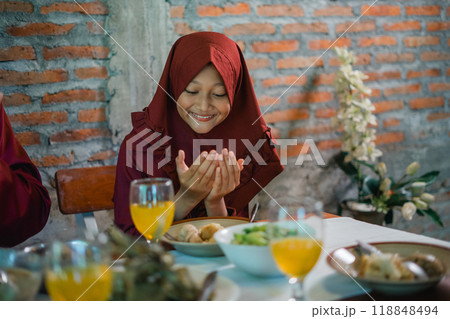 Joyful Moment at a Family Meal: A Young Girl in a Red Hijab Expresses Gratitude 118848494
